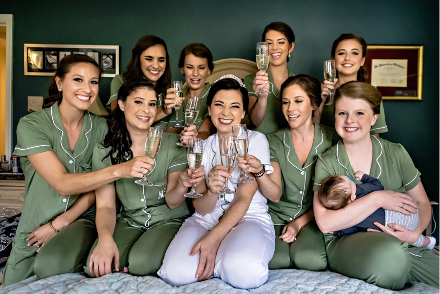 A bride and her bridesmaids toast champagne on her childhood bed before the wedding.